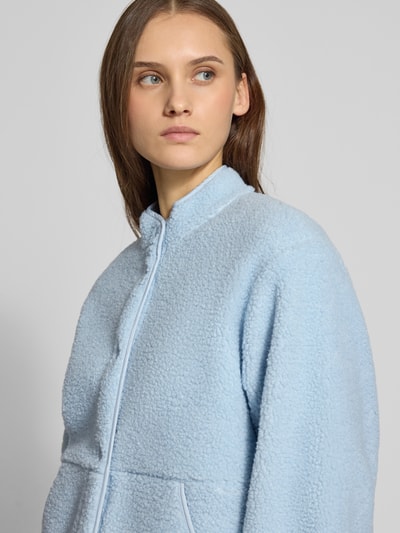 Frauenmodel trägt hellblaue Relaxed Fit Fleecejacke mit Stehkragen Modell 'VERA' von JJXX aus Teddyfell, Knopfleiste, Eingrifftaschen, Nahaufnahme Oberkörper, Rückenlänge 57 cm, Schulterbreite 41 cm, Brustweite 53 cm, Ärmellänge 54 cm.