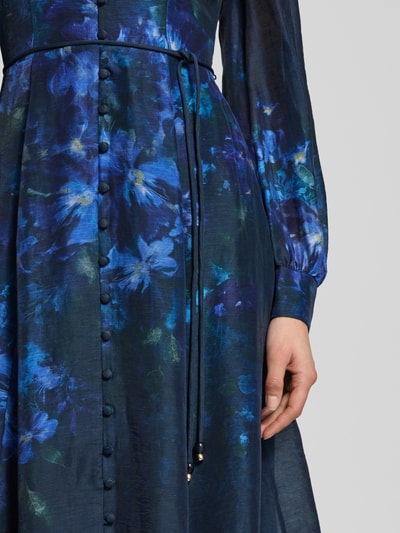 Vrouwenmodel draagt midi-jurk van lyocellmix met strikceintuur model 'Kahlani' van Forever New, bloemmotief in blauw en paars, detailopname
