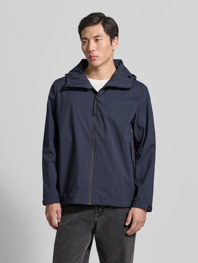Männermodel trägt Herren Jacke mit Kapuze und Reißverschlusstaschen Modell 'CYCLONE' von GOFRANCK, Farbe Dunkelblau, Reine Baumwolle, Gerader-Schnitt, Label-Detail, verstellbare Ärmelriegel mit Klettverschluss, Ganzkörperansicht von vorne.