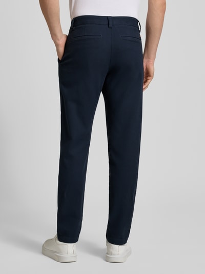 Männermodel trägt dunkelblaue Tapered Fit Chino aus Baumwoll-Mix Modell 'CHINO PLEATED' von BOSS Orange, Ganzkörperansicht Rückansicht.