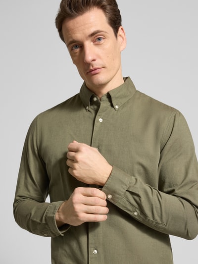 Männermodel trägt Slim Fit Freizeithemd aus reiner Baumwolle von MCNEAL in Olivgrün, Button-Down-Kragen, Nahaufnahme Oberkörper.