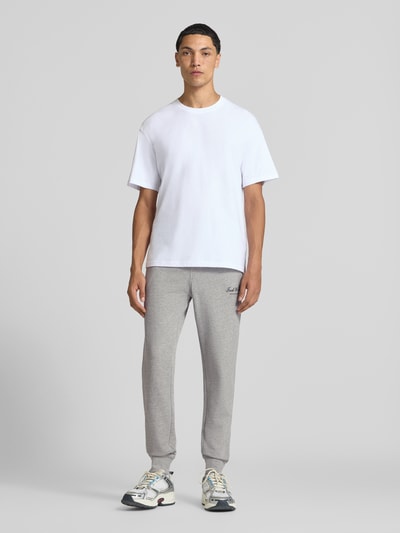 Männermodel trägt sweatpants met labelprint Model 'GORDON' van JACK & JONES, los model, elastische band met tunnelkoord, zij-steekzakken, binnenbeenlengte bij maat M 77 cm, ganzkörperansicht van voren.