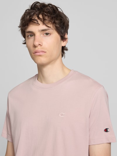 Männermodel trägt T-Shirt mit Label-Stitchings und Rundhalsausschnitt von Champion in zartem Rosaton, reine Baumwolle, Regular Fit, Nahaufnahme Oberkörper.