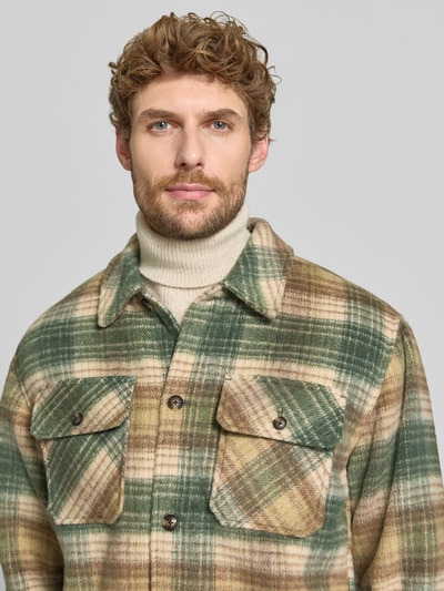 Männermodel trägt Regular Fit Hemdjacke mit Brusttaschen von Scotch & Soda, kariertes Muster in Grün und Beige, Nahaufnahme Oberkörper.