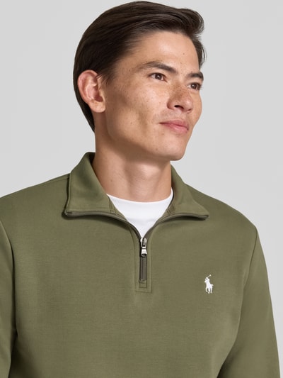 Męski model nosi Regular Fit Troyer aus Baumwoll-Mix von Polo Ralph Lauren w kolorze oliwkowym, widok z przodu, zbliżenie na górę ciała.