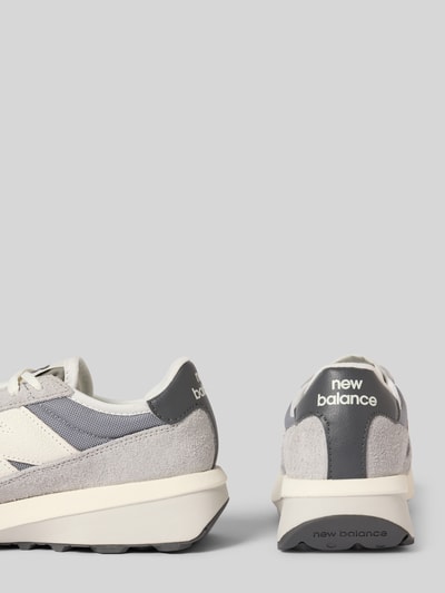 Produktfoto, Sneaker mit Label-Detail Modell 'U370AH' von New Balance in Grau und Weiß, abgerundete Form, Schnürung, strukturierte Sohle, Absatzhöhe 5 cm, Schafthöhe 7 cm, Schaftweite 7 cm.