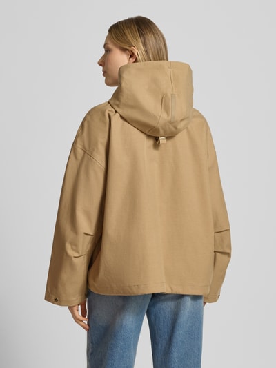 Frauenmodel trägt Jacke mit Kapuze und versiegelten Nähten Modell 'ELLE' von G-LAB aus Lyocell-Mix mit Leinen-Anteil in Beige, Gerader-Schnitt, Wasserdicht, Winddicht, Atmungsaktiv, Druckknopfverschluss, seitliche Pattentaschen, Ganzkörperansicht Rückansicht.
