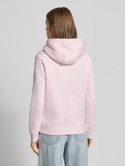 Frauenmodel trägt Regular Fit Hoodie aus Baumwoll-Mix von Tommy Jeans, różowy, gładki, długi rękaw, ściągacze, widok całej sylwetki z tyłu.