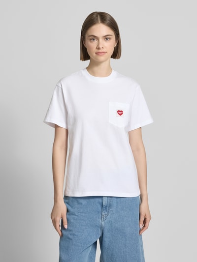 Frauenmodel trägt Damen T-Shirt mit Label-Patch von Carhartt Work In Progress in Weiß aus Reine Baumwolle, Gerader-Schnitt, Rundhalsausschnitt, Brusttasche, Rückenlänge bei Größe S: 58 cm, Ganzkörperansicht von vorne.