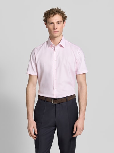 Männermodel trägt Regular Fit Business-Hemd mit Kentkragen von Christian Berg Men in Hellrosa aus Reine Baumwolle, Kurzärmelig, Knopfleiste, Rückenlänge 81 cm, Schulterbreite 49 cm, Ärmellänge 24 cm, Ganzkörperansicht von vorne.