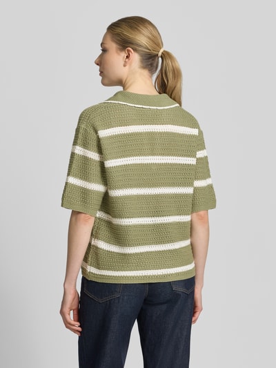 Frauenmodel trägt Regular Fit Poloshirt aus Baumwoll-Mix von s.Oliver RED LABEL mit grün-beigem Allover-Streifenmuster und Polokragen, Stricktextur, Rippen an Ärmeln und Saum, Ganzkörperansicht Rückansicht.