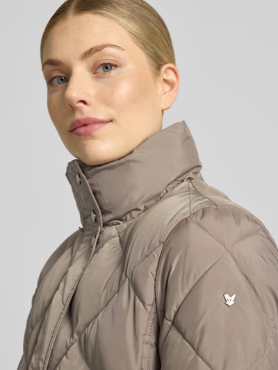 Frauenmodel trägt Regular Fit Mantel in Stepp-Optik von FUCHS SCHMITT in Beige mit Kapuze und Stehkragen, Nahaufnahme Oberkörper. Damen Mantel mit Eingrifftaschen, Rückenlänge 84 cm, Schulterbreite 42 cm, Brustweite 47 cm, Ärmellänge 64 cm.