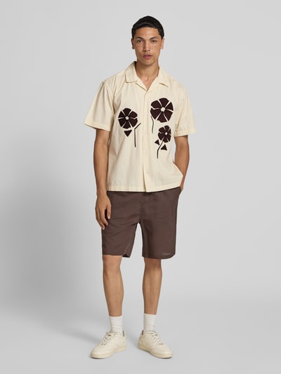 Männermodel trägt Loose Fit Freizeithemd aus reiner Baumwolle Modell 'SEEREN EMBROIDERY' von Only & Sons in Creme mit braunen Stickereien, kombinierbar für Herren, Ganzkörperansicht von vorne.