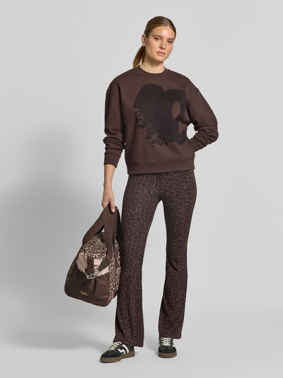 Vrouwenmodel draagt Oversized Sweatshirt aus Baumwolle van Lala Berlin in bruin met motiefprint, ribboorden, puur katoen, ruglengte maat S 60 cm, Ganzkörperansicht van voren.