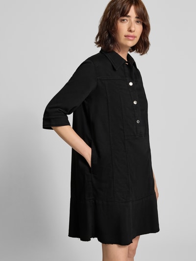 Frauenmodel trägt knielanges Hemdblusenkleid mit Knopfleiste und 1/2-Arm von Marc Cain in Schwarz, gerader Schnitt, Nahaufnahme Oberkörper.