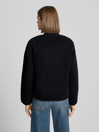 Frauenmodel trägt kurtka z polaru z Futerko, krój regular fit, Model 'Janet' od Carhartt Work In Progress, stójka, zamek błyskawiczny dwustronny, wpuszczane kieszenie, Brustasza, detal z logo, Długość tyłu w rozmiarze S: 80 cm, szerokość ramion w rozmiarze S: 38 cm, szerokość klatki piersiowej w rozmiarze S: 52 cm, długość rękawów w rozmiarze S: 62 cm, Ganzkörperansicht Rückansicht.