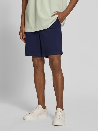 Männermodel trägt Regular Fit Chinoshorts aus Baumwoll-Mix Modell 'CHINO' von Armedangels, unifarben navy, Baumwollstruktur, Nahaufnahme Oberkörper bis Knie.