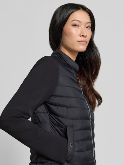 Kobieta modelka nosi Jacke aus Baumwoll-Mix in Stepp-Optik von FUCHS SCHMITT, czarny kolor, miękka faktura, z efektem pikowania, mieszanka bawełny, krój taliowany, kaptur z tunelem, zamek błyskawiczny dwustronny, Długość tyłu w rozmiarze 36: 59 cm, Szerokość ramion w rozmiarze 36: 40 cm, Szerokość klatki piersiowej w rozmiarze 36: 48 cm, Długość rękawów w rozmiarze 36: 67 cm, z przodu ujęcie górnej części ciała