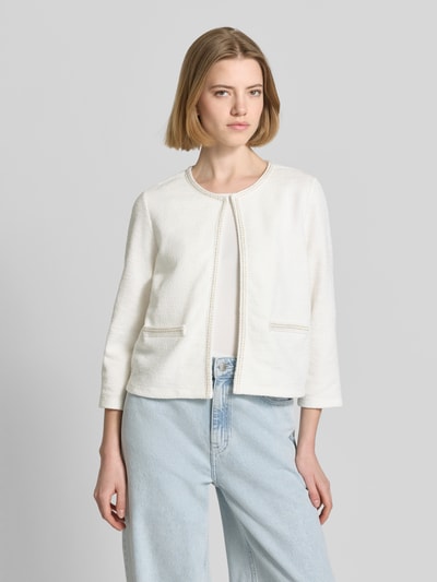 Modelka nosi Regular Fit Jacke mit Zierbordüre von More & More, biały kolor, bawełniany materiał, faktura lekko ziarnista, przód z otwartym designem, kobieca kurtka, długość tyłu 48 cm, długość rękawa 47 cm, krój regular fit, widok całej sylwetki z przodu.