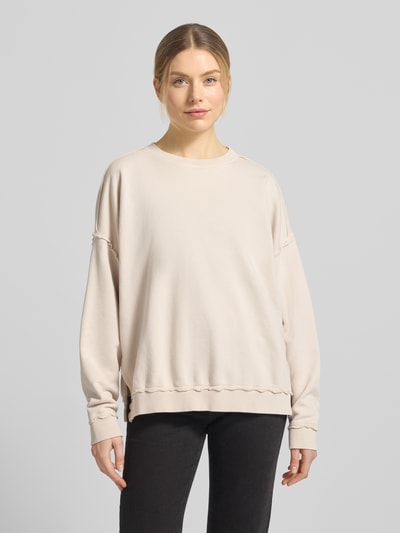 Modelka nosi Oversized Fit Sweatshirt mit Zier-Bordüren od Smith and Soul, mieszanka bawełny, krój oversized fit, okrągły dekolt, ozdobne bordiury, jasny kolor, gładka faktura, widok całej sylwetki z przodu.