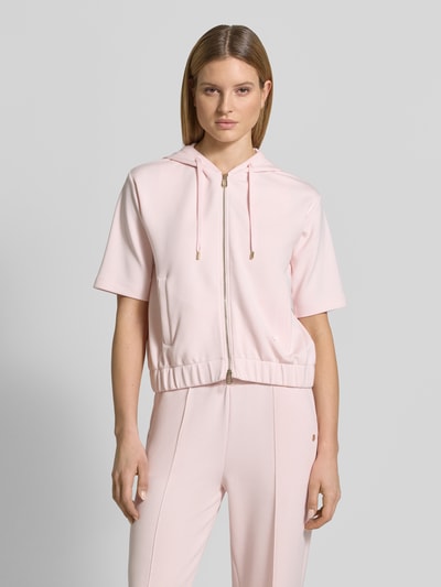 Frauenmodel trägt Sweatjacke mit Halbarm Modell 'Therese' von JOOP! in zartem Rosa, Elastischer-Material-Mix, Gerader-Schnitt, Kapuze mit Tunnelzug, Reißverschluss, Label-Detail, Elastischer Bund, Eingrifftaschen, Ganzkörperansicht von vorne.