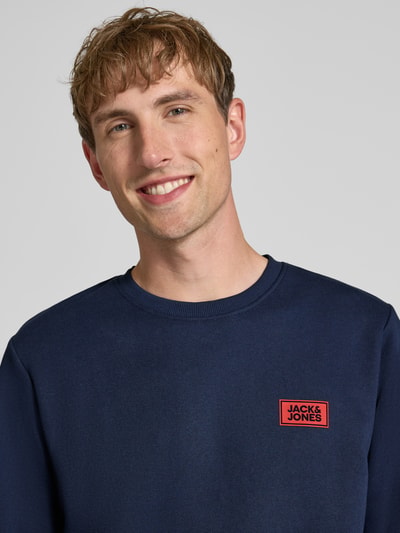 Männermodel trägt donkerblauw sweatshirt met labelprint Model 'RUSH' van JACK & JONES, katoenmix, los model, ronde hals, ribboorden, Nahaufnahme Oberkörper.