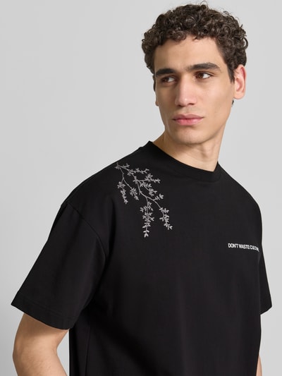 Männermodel trägt Relaxed Fit T-Shirt aus Baumwoll-Mix von Don't Waste Culture mit Motiv-Print, Label-Print, Rundhalsausschnitt, Nahaufnahme Oberkörper.