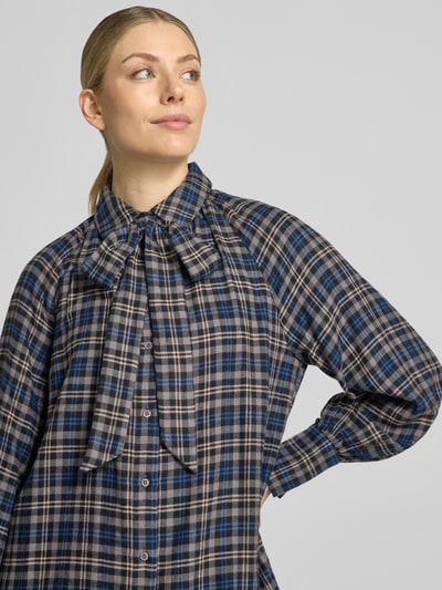 Frauenmodel trägt Regular Fit Hemdbluse aus Viskose-Mix von Oui im karierten Muster mit Hemdblusenkragen und Zierschleife, Nahaufnahme Oberkörper.