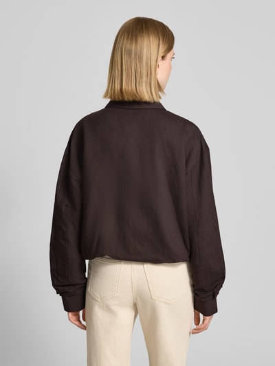 Frauenmodel trägt Jacke mit Umlegekragen Modell 'Nisari' von Someday aus reiner Baumwolle in Dunkelbraun, strukturierte Oberfläche, Regular Fit, Knopfleiste und Tunnelzug, kombiniert mit heller Hose, Ganzkörperansicht Rückansicht.