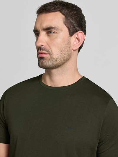 Männermodel trägt T-Shirt mit Rundhalsausschnitt und Label-Stitching von Fynch-Hatton in Olivgrün, reine Baumwolle, Nahaufnahme Oberkörper.