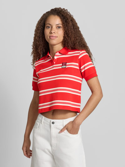 Frauenmodel trägt Cropped Poloshirt mit Label-Patch von Karo Kauer in Rot mit weißen Streifen, Material-Mix, Straight Fit, Polokragen, kurze Knopfleiste, Damen, Rückenlänge bei Größe S: 47 cm, Ganzkörperansicht von vorne.