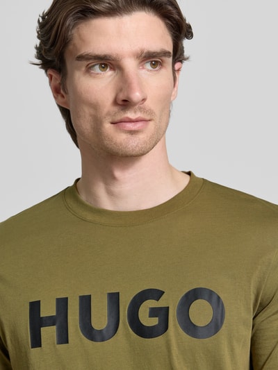 Männermodel trägt Regular Fit T-Shirt aus reiner Baumwolle Modell 'DULIVIO' von HUGO, Optik: Unifarben, Label-Print, Nahaufnahme Oberkörper.