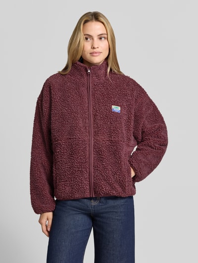 Frauenmodel trägt Regular Fit Jacke aus Teddyfell Modell 'Hoktown' von American Vintage in Bordeaux mit Stehkragen, Logo-Patch und Reißverschluss, strukturierte Oberfläche, Ganzkörperansicht von vorne. Rückenlänge 63 cm, Schulterbreite 52 cm, Brustweite 51 cm, Ärmellänge 54 cm.