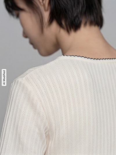 Frauenmodel trägt Strickshirt mit Rundhalsausschnitt von Jake*s Collection aus reiner Baumwolle, semitransparente Textur, Detailaufnahme Rückansicht.
