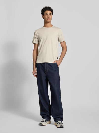 Männermodel trägt Regular Fit T-Shirt mit Logo-Detail von Replay, reine Baumwolle, Rundhalsausschnitt, dunkelblaue Hose, Ganzkörperansicht von vorne.