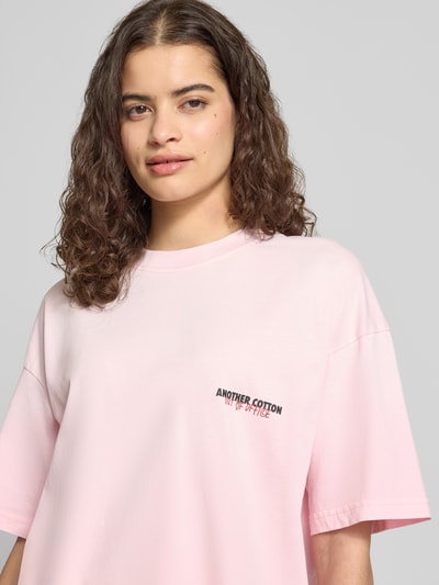 Kobiece modelka nosi Oversized T-Shirt mit Label-Print von ANOTHER COTTON LAB, różowy, bawełna, okrągły dekolt, długość tyłu w rozmiarze S: 58 cm, z nadrukiem z logo, półzbliżenie przód.