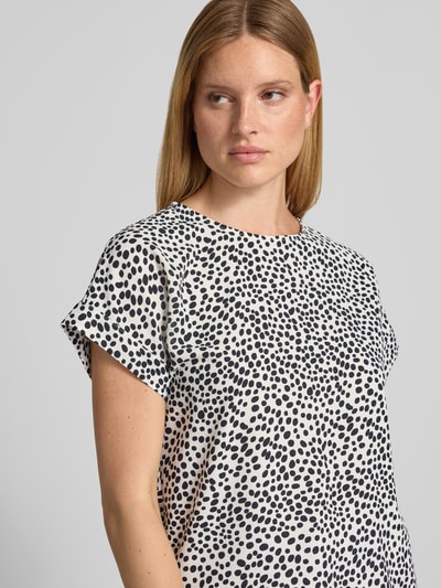 Frauenmodel trägt Blusenshirt im Allover-Look Modell 'JOSA' von Vila, Weiß mit schwarzen Punkten, Regular Fit, Nahaufnahme Oberkörper.