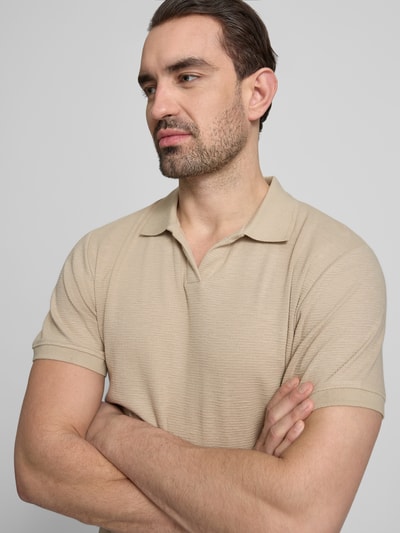 Męski model nosi Comfort Fit Poloshirt mit V-Ausschnitt von Lindbergh z bawełny, fakturowany wzór, detal z logo, długość tyłu 68 cm, rozmiar M, z przodu zbliżenie na górną część ciała.