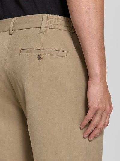 Männermodel trägt beige Loose Fit Bundfaltenhose mit Viskose-Anteil Modell '220-LOOSE' von Selected, Detailaufnahme Rückansicht.
