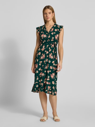 Frauenmodel trägt Kleid aus Viskose mit Bindegürtel und Volantsaum von Apricot, grünes Midikleid mit floralem Muster, taillierter Schnitt, V-Ausschnitt, kurze Knopfleiste, Rückenlänge 94 cm, Brustweite 51 cm, Ärmellänge 7 cm, Ganzkörperansicht von vorne.