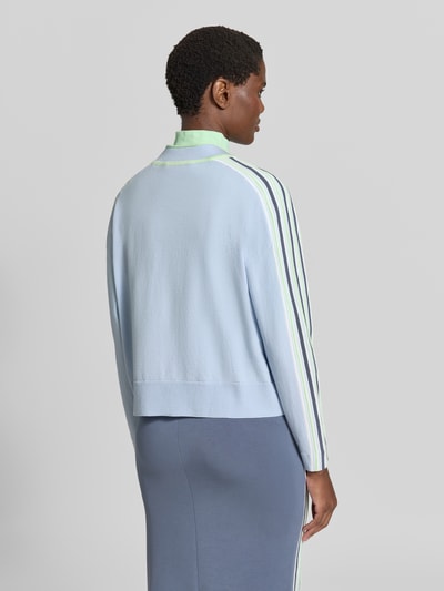 Frauenmodel trägt Strickjacke aus Lyocell-Mix mit Knopfleiste von Marc Cain, lockere Passform, Kontraststreifen, Ganzkörperansicht Rückansicht.