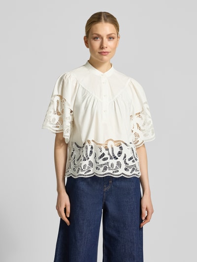 Frauenmodel trägt Regular Fit Bluse mit Spitze Modell 'LINDA' von SUNCOO PARIS aus weißer Baumwolle mit Stehkragen und Knopfleiste, Ganzkörperansicht von vorne.