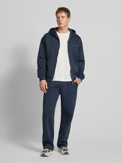 Männermodel trägt Regular Fit Sweatjacke mit Reißverschluss von Review in Dunkelblau, Baumwoll-Mix, Logo-Print, Kapuze, Ganzkörperansicht von vorne