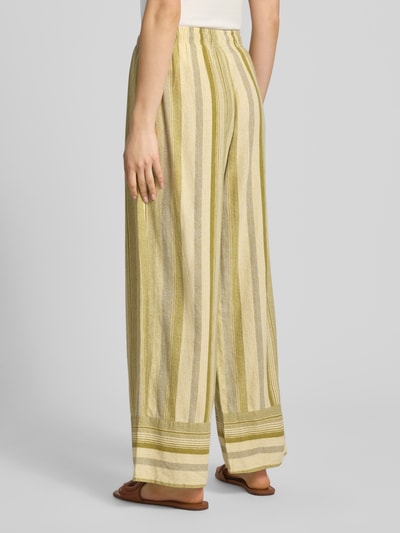 Kobiece modelka nosi Hose aus Leinen-Viskose-Mix mit elastischem Bund Modell 'POLLY' od Topshop, beżowo-oliwkowe pionowe pasy, prosty krój, miękka tekstura, szerokość w rozmiarze 36: 34 cm, długość nogawki wewnętrznej: 76 cm, widok całej sylwetki z tyłu.