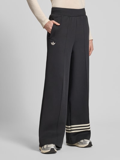 Frauenmodel trägt Wide Leg Sweatpants aus Baumwoll-Mix Modell 'NEUCL' von adidas Originals, Optik: Unifarben mit Logo-Stitching, Kontraststreifen, Reißverschlusstaschen, Ganzkörperansicht von vorne.