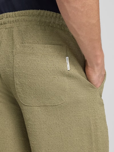 Männermodel trägt Regular Fit Sweatshorts aus Baumwoll-Mix von Marc O'Polo Denim, Optik: Unifarben, Bouclé-Struktur, Label-Patch, Detailaufnahme Gesäßtasche.