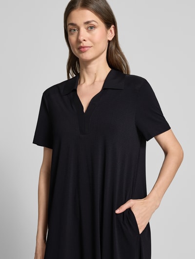 Frauenmodel trägt Midikleid mit Strukturmuster und Umlegekragen Modell 'JOSEPHINA' von Raffaello Rossi, Material-Mix mit Stretch-Anteil, V-Ausschnitt, Loose-Fit, schwarze Farbe, sichtbare Taschen, Nahaufnahme Oberkörper.