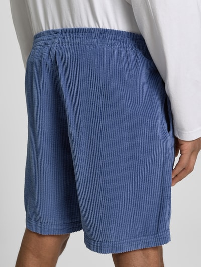 Männermodel trägt Shorts mit elastischem Bund Modell 'PADOW' von American Vintage aus reiner Baumwolle in Blau, Detailaufnahme Rückansicht.