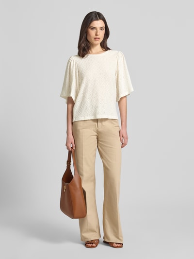 Kobieta modelka nosi Blusenshirt mit Lochstickerei Modell 'KIONA' von FREE/QUENT, mieszanka materiałów z dodatkiem streczu, krój regular fit, haft angielski, okrągły dekolt, długość tyłu w rozmiarze S 55 cm, długość rękawów w rozmiarze S 33 cm, jasne kolory, szerokie rękawy, proste beżowe spodnie, całkowity widok z przodu.