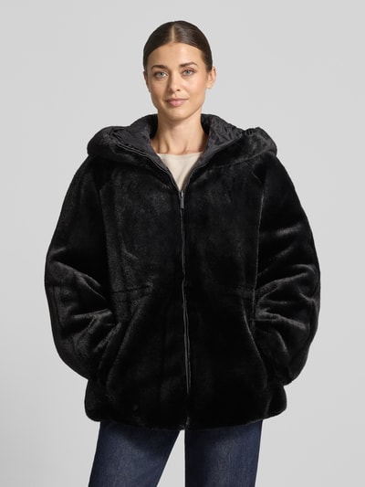 Frauenmodel trägt Kunstfelljacke mit Kapuze von Emporio Armani in Schwarz, samtige Optik, seitliche Taschen, Ganzkörperansicht von vorne.